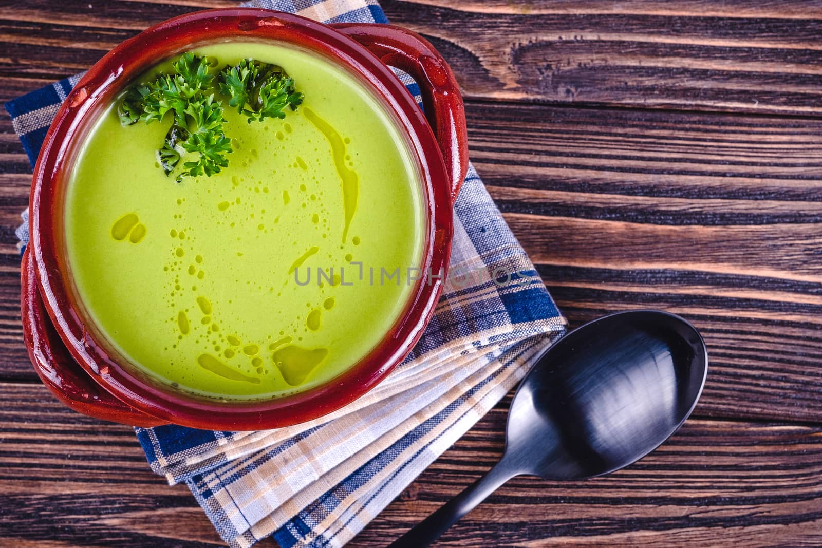 Fresh asparagus creamy soup and ingredients on wooden table on rustic wooden background, selective focus