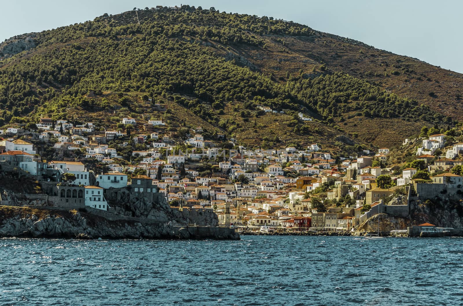 Saronic sea view of the panorama that we find when arriving at the port of the island of hydra with the entrance to it the city and the mountain in the background. Port that historically was fishing today lives of tourism.