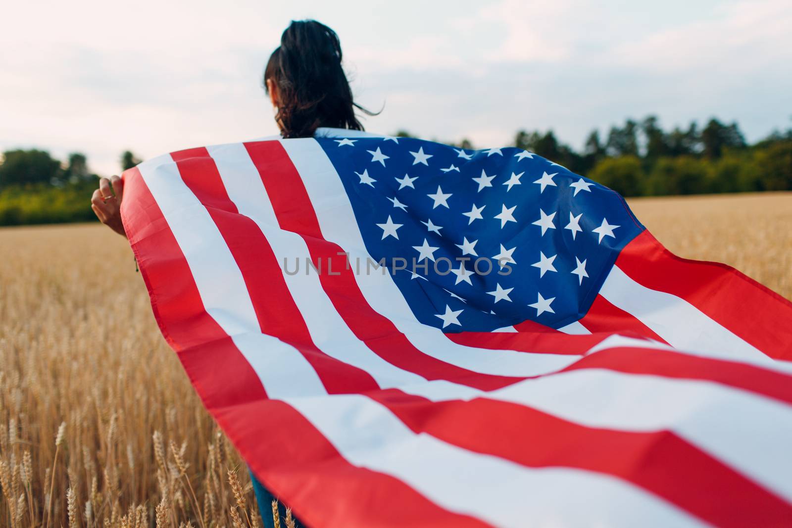 Woman with American flag in field at sunset. 4th of July. Independence Day patriotic holiday. by primipil