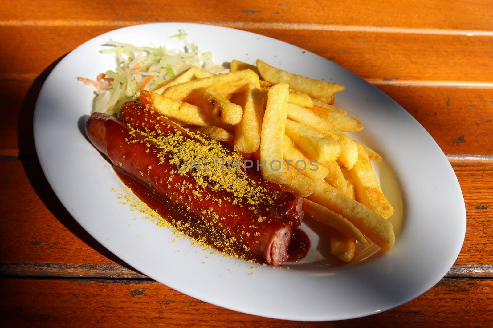 Traditional German currywurst, served with chips on a white plat by MP_foto71
