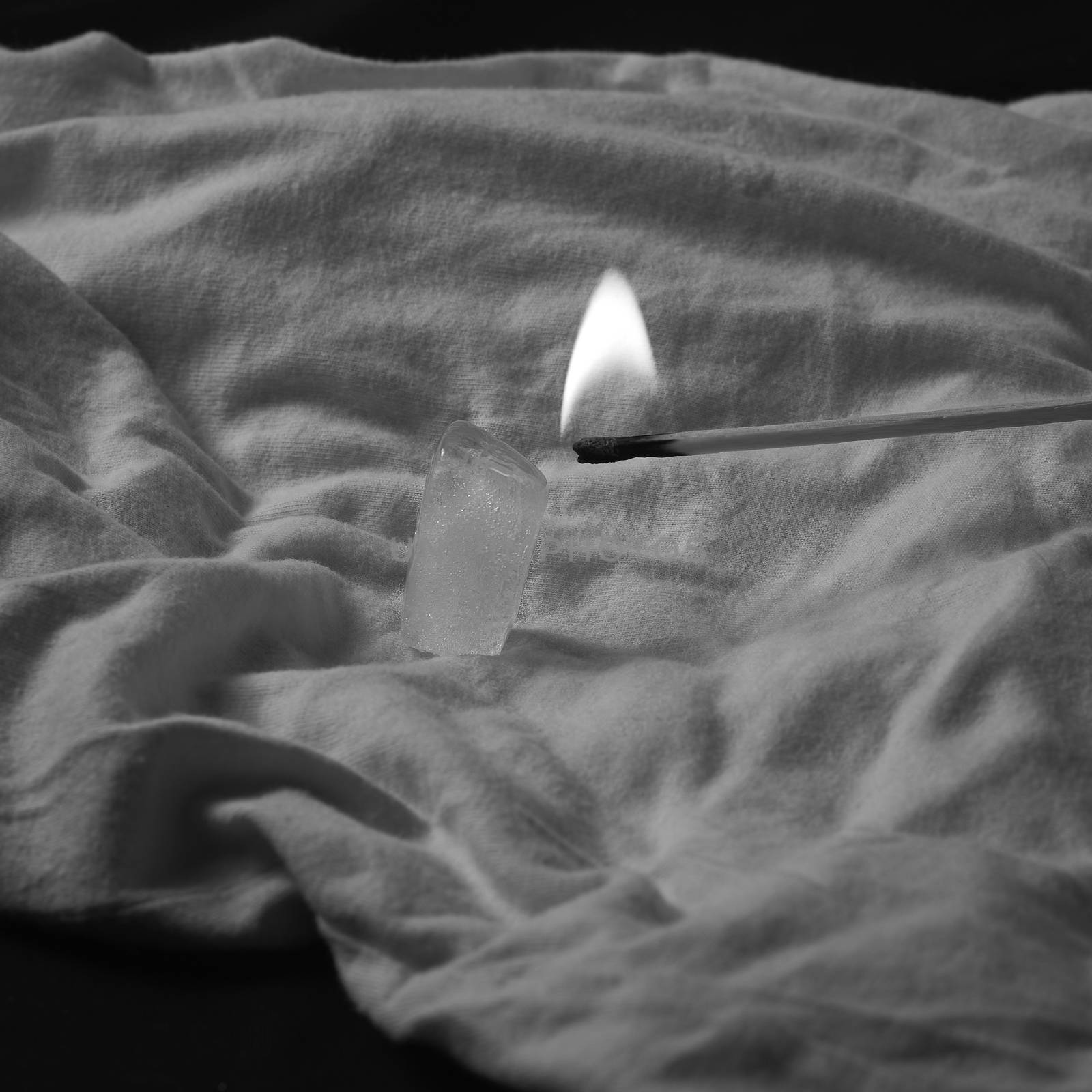 Burning match melting ice cube, black and white, white background