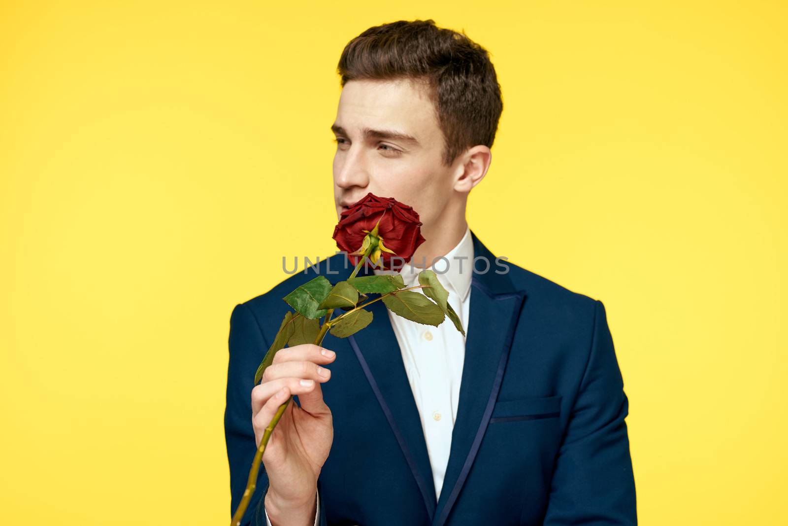 Gentleman in classic suit on yellow background with red rose romance cropped view. High quality photo