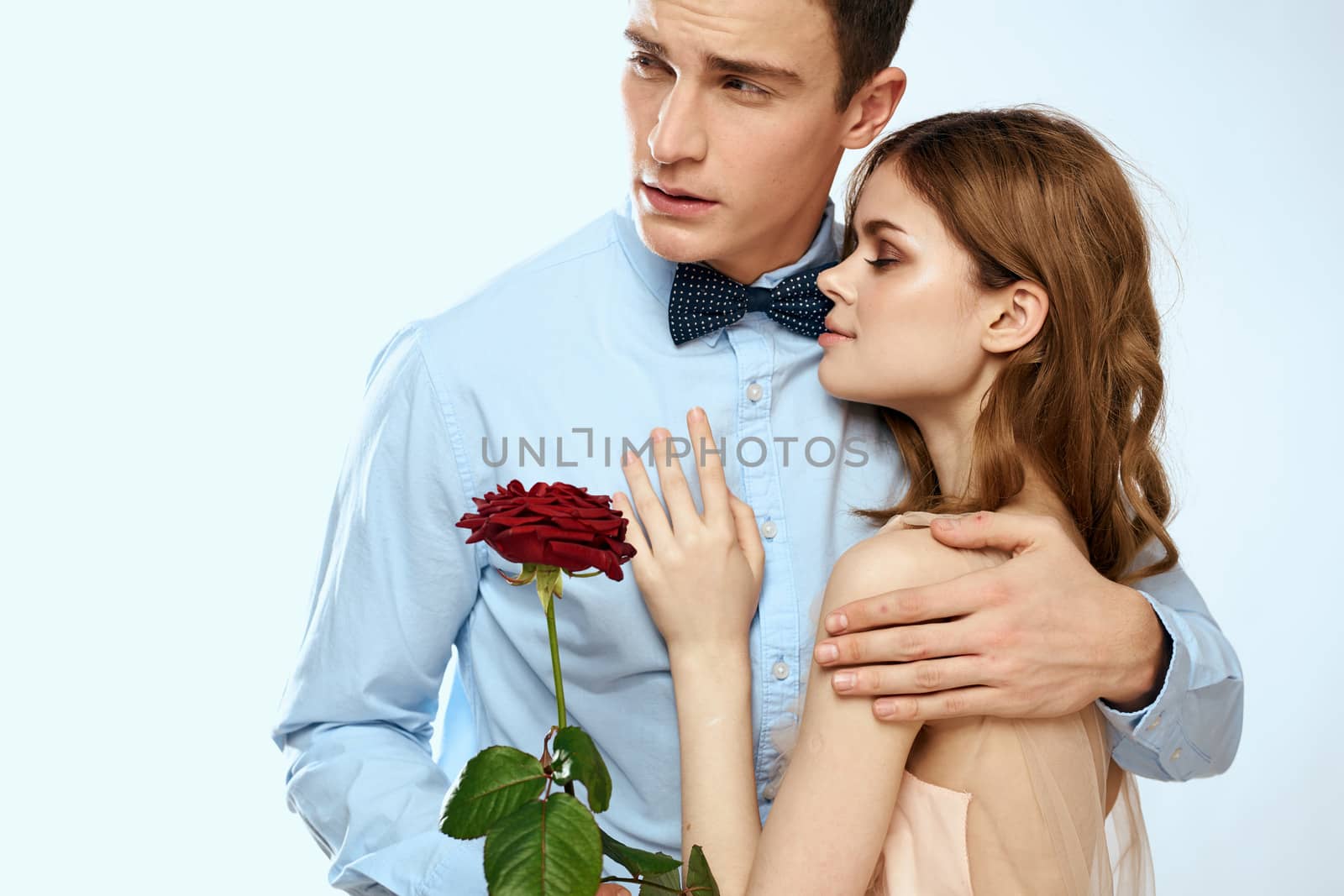Man and woman with a red rose on a light background love family hugs by SHOTPRIME
