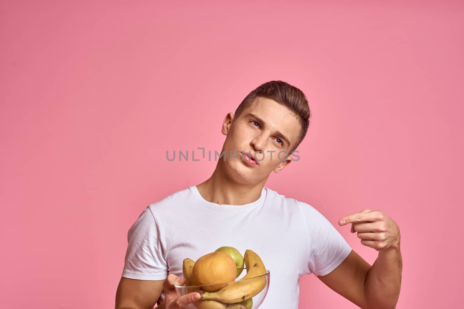 Man with fruits in hands on a pink background healthy food vitamins pink background white t-shirt model by SHOTPRIME