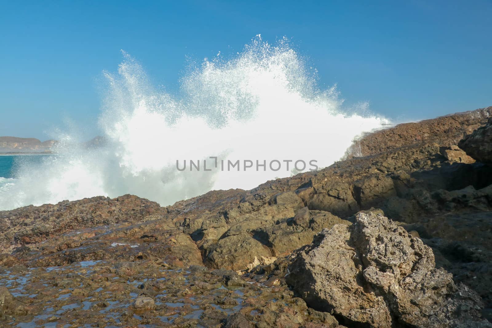 Ocean waves crashing on to lava rocks, Big Island of Lombok, Indonesia.