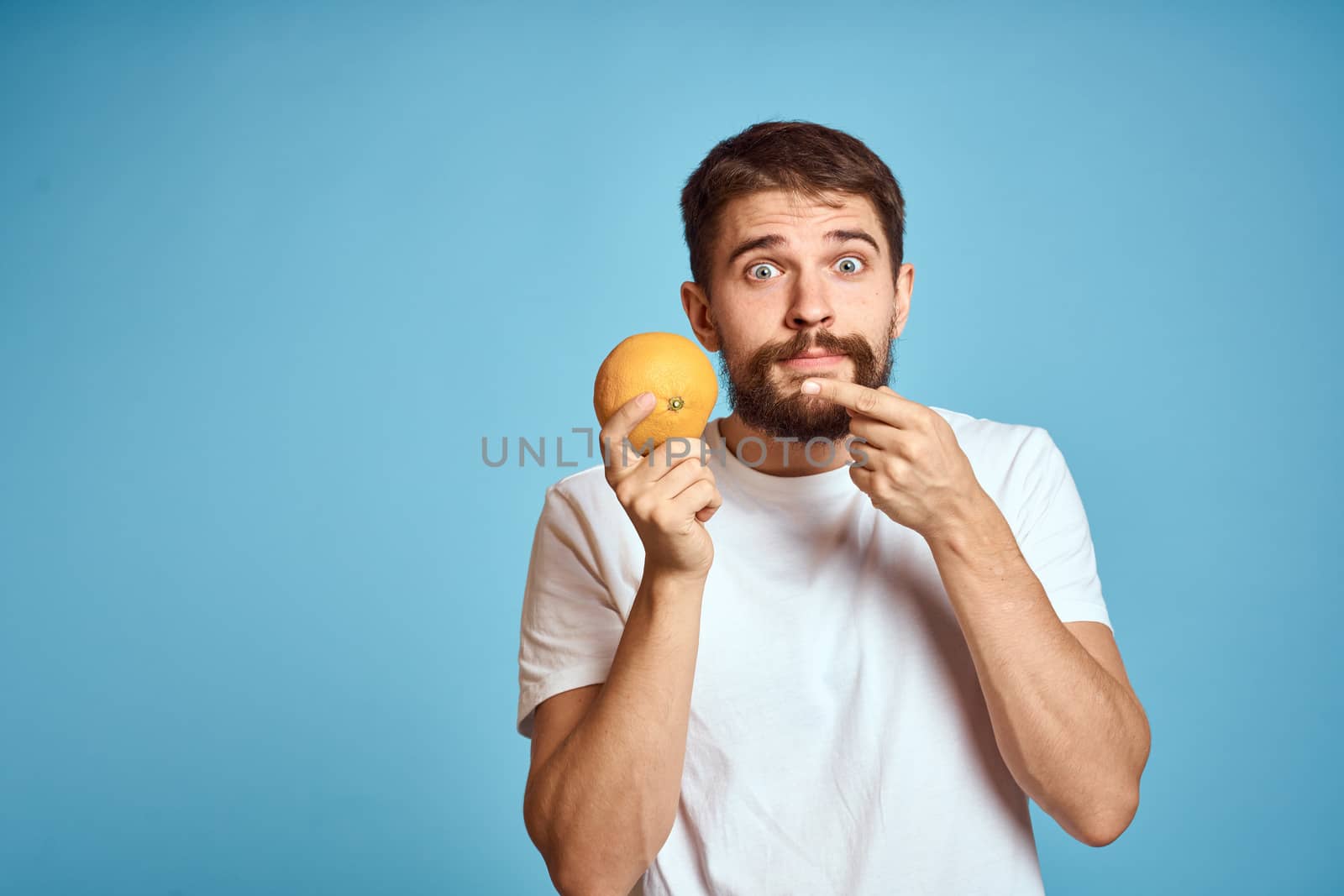 man with orange on blue background and cropped view Copy Space gesturing with hands by SHOTPRIME