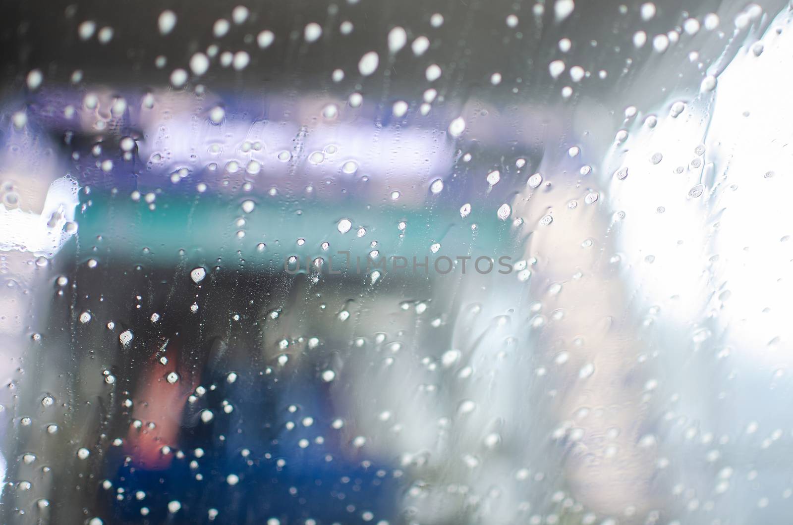 View from inside a car being washed at a car wash from the driver seat. Auto inside carwash from interior. Car windshield cleaning. Automatic conveyorized tunnel vehicle wash.