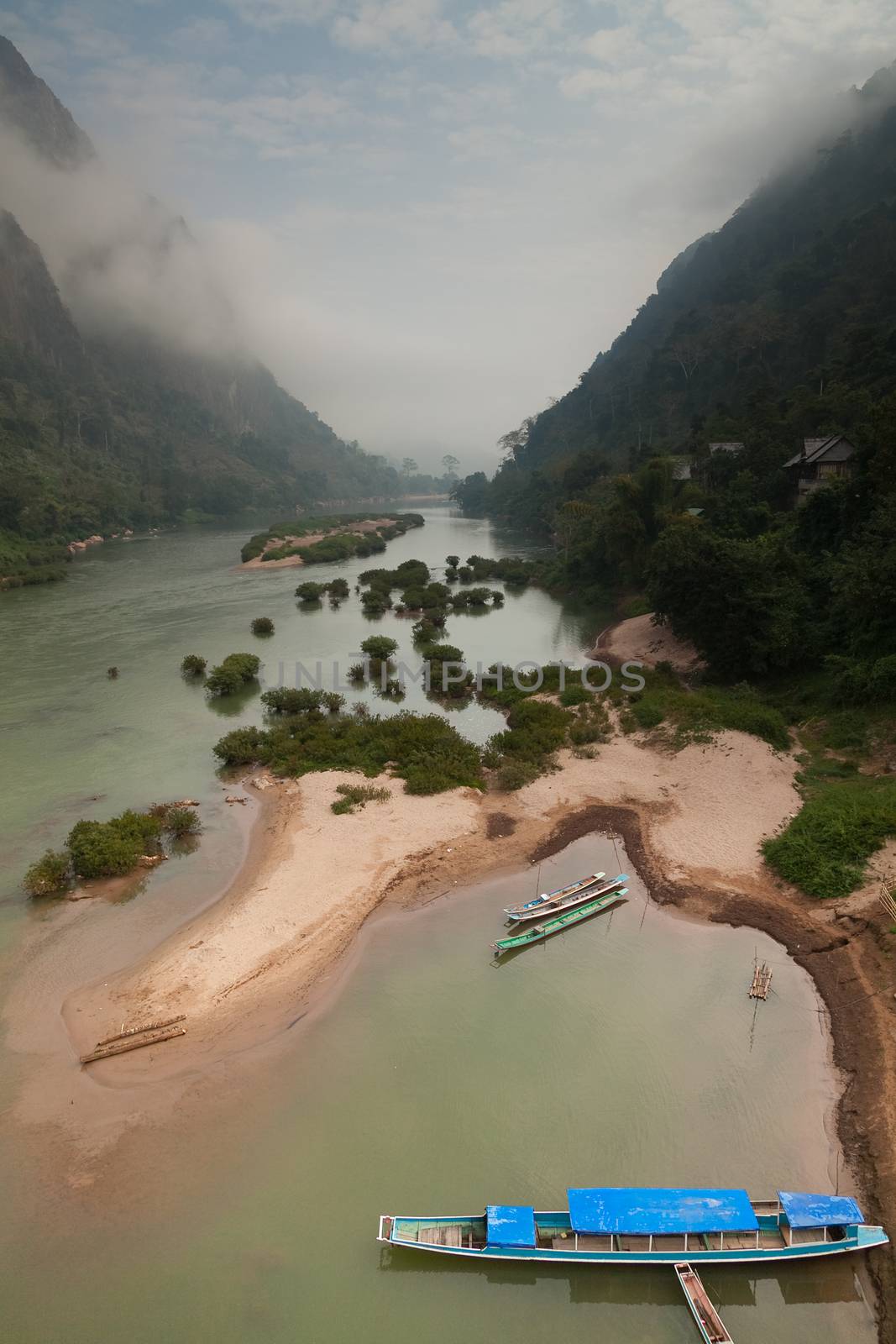 Nam Ou River, boats and landscape with mountains and riverside villages by kgboxford