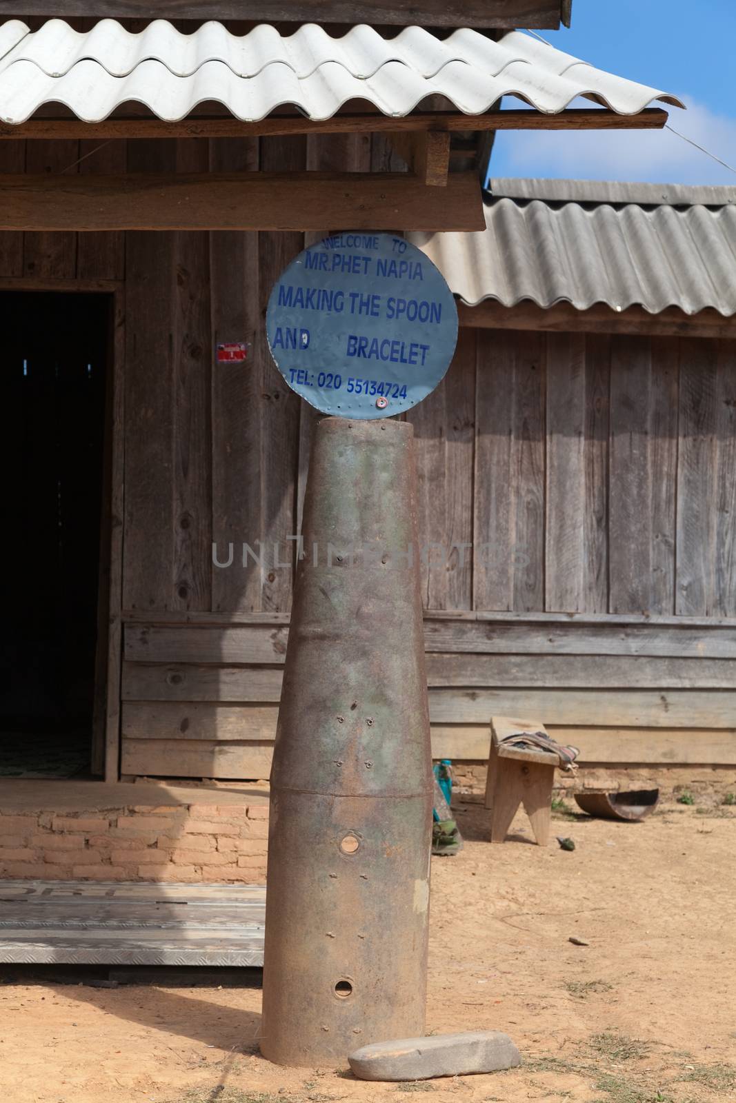 Ban Napia near Phonsavan Laos a village sign supported on shell casing from bomb where people makes spoons from bombs leftover from Vietnam war. High quality photo