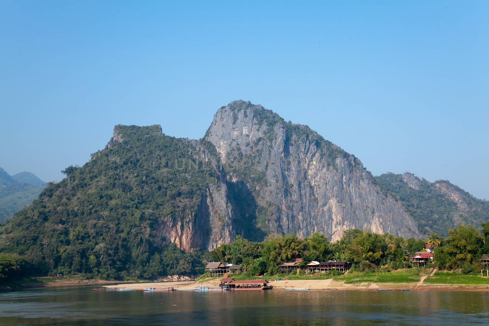 Nam Ou River, boats and landscape with mountains and riverside villages by kgboxford