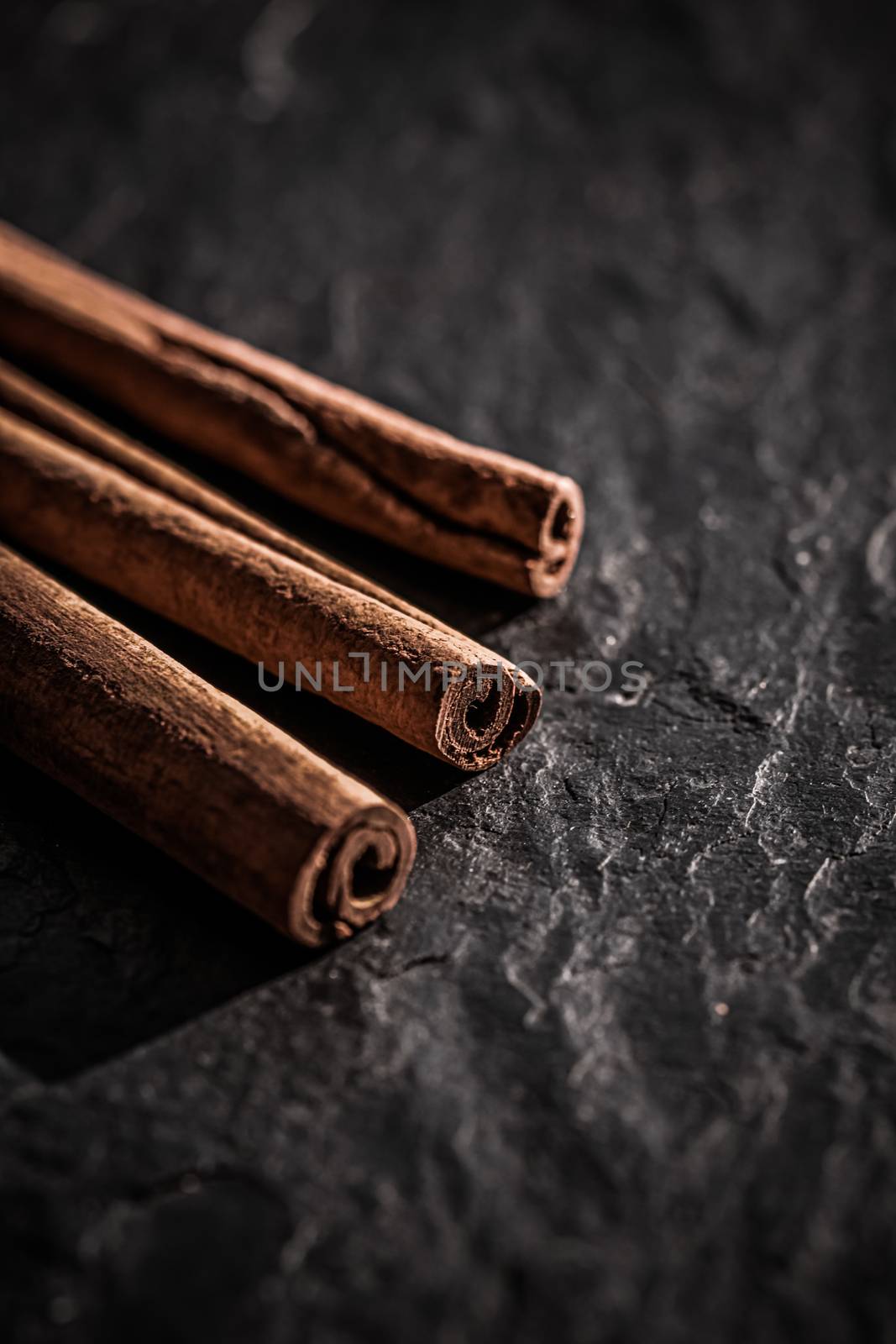 Cinnamon sticks on black stone background, food recipe by Anneleven