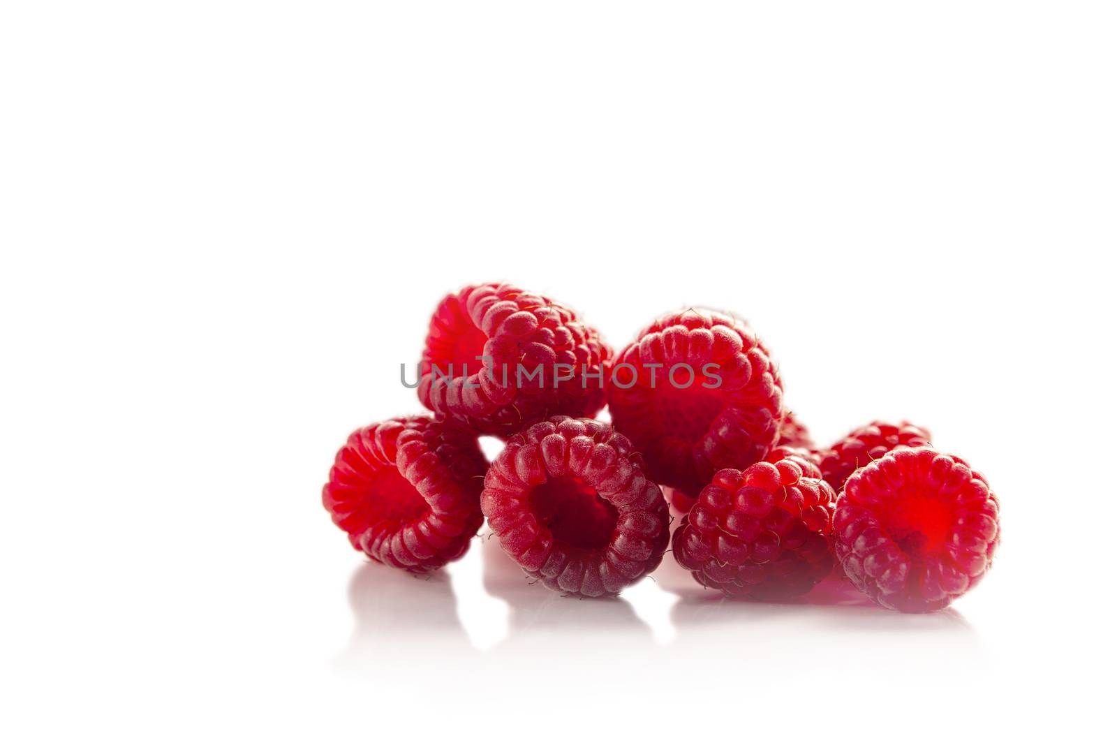 Fruits of a garden raspberry heaped lie with reflection on a white background