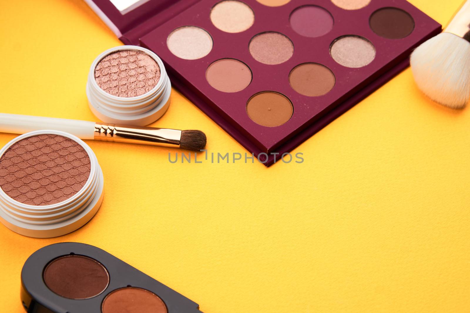 Professional eyeshadows and makeup brushes on a yellow background make-up decoration by SHOTPRIME