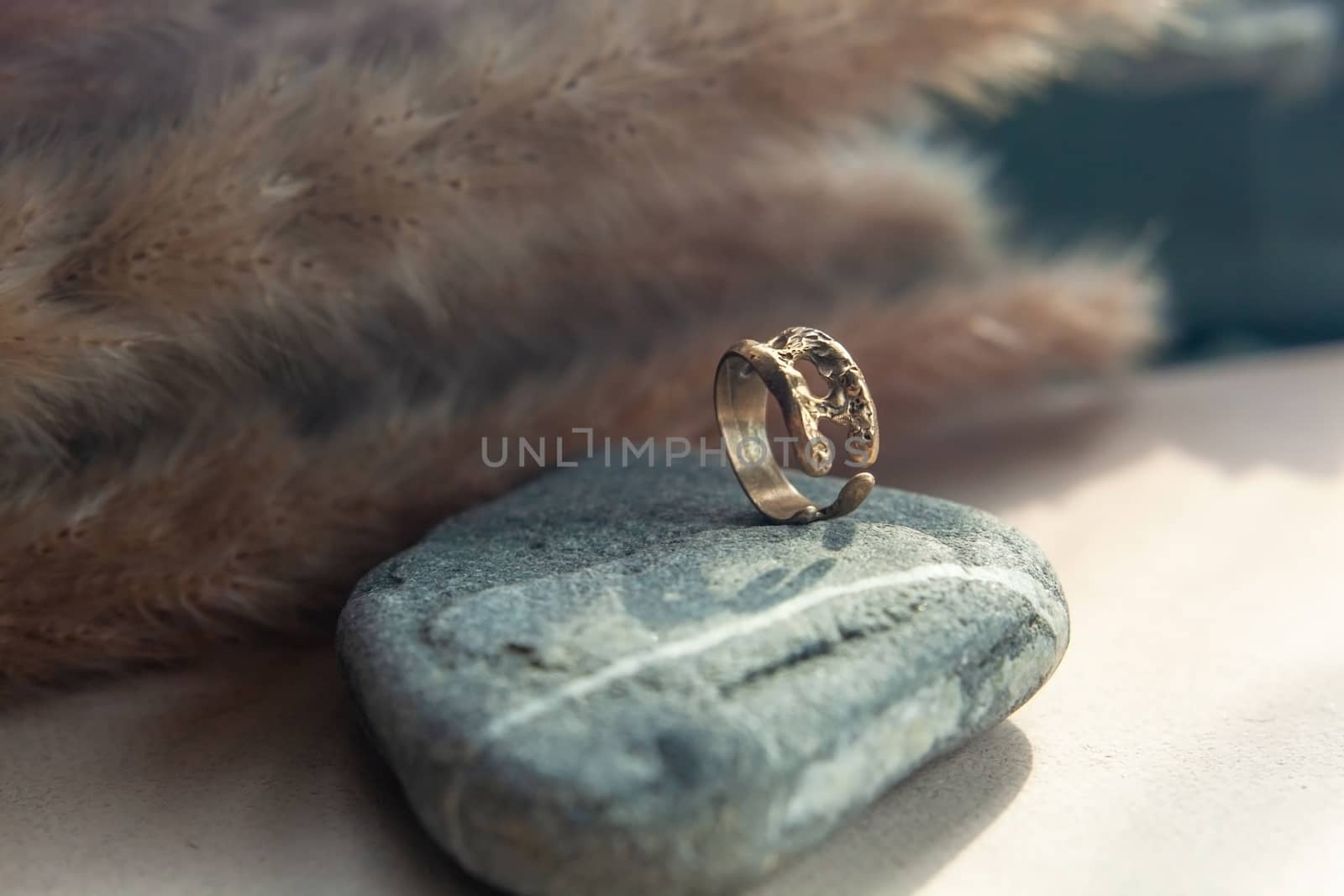 trendy vintage cast brass ring. jewelry womens ring abstract drawing closeup on a gray natural stone with shaddows