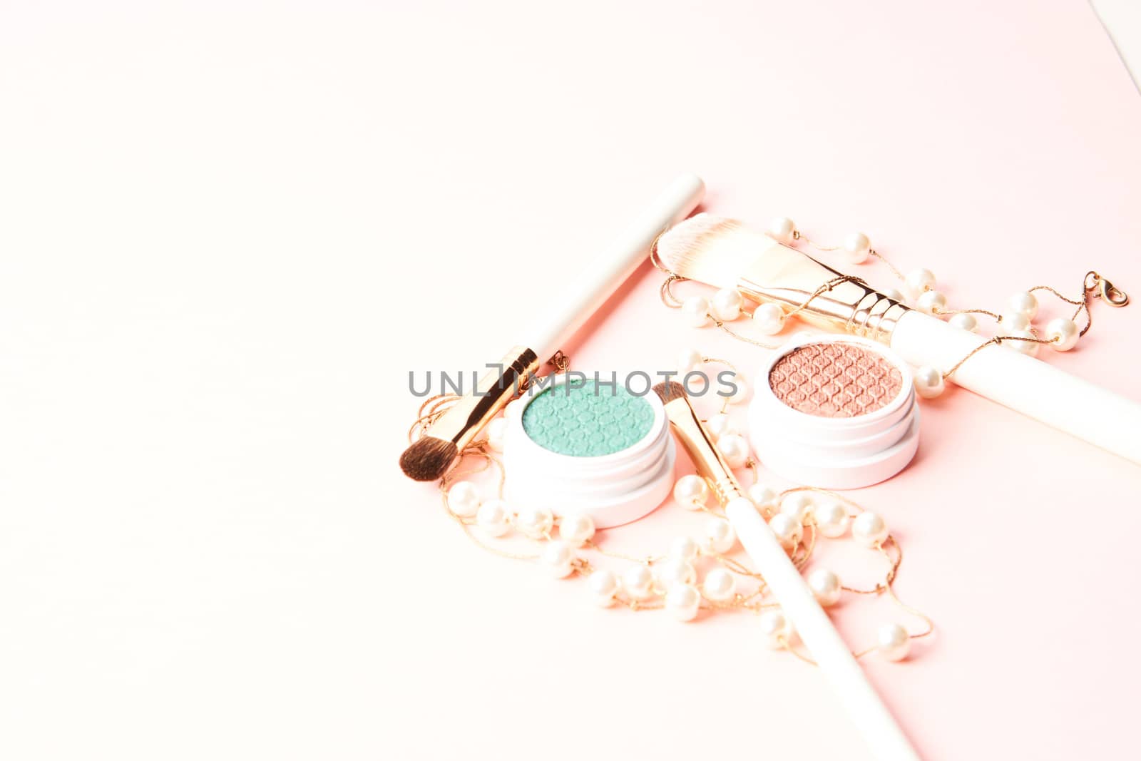 Makeup brushes, eyeshadows, decorative cosmetics and beads on a light background by SHOTPRIME