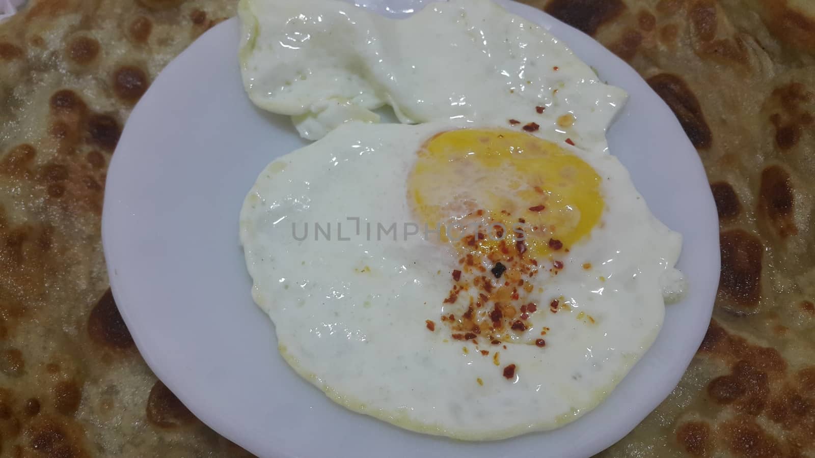 Top view of Fried egg or egg omelet on a white saucer or plate served with spines on it.