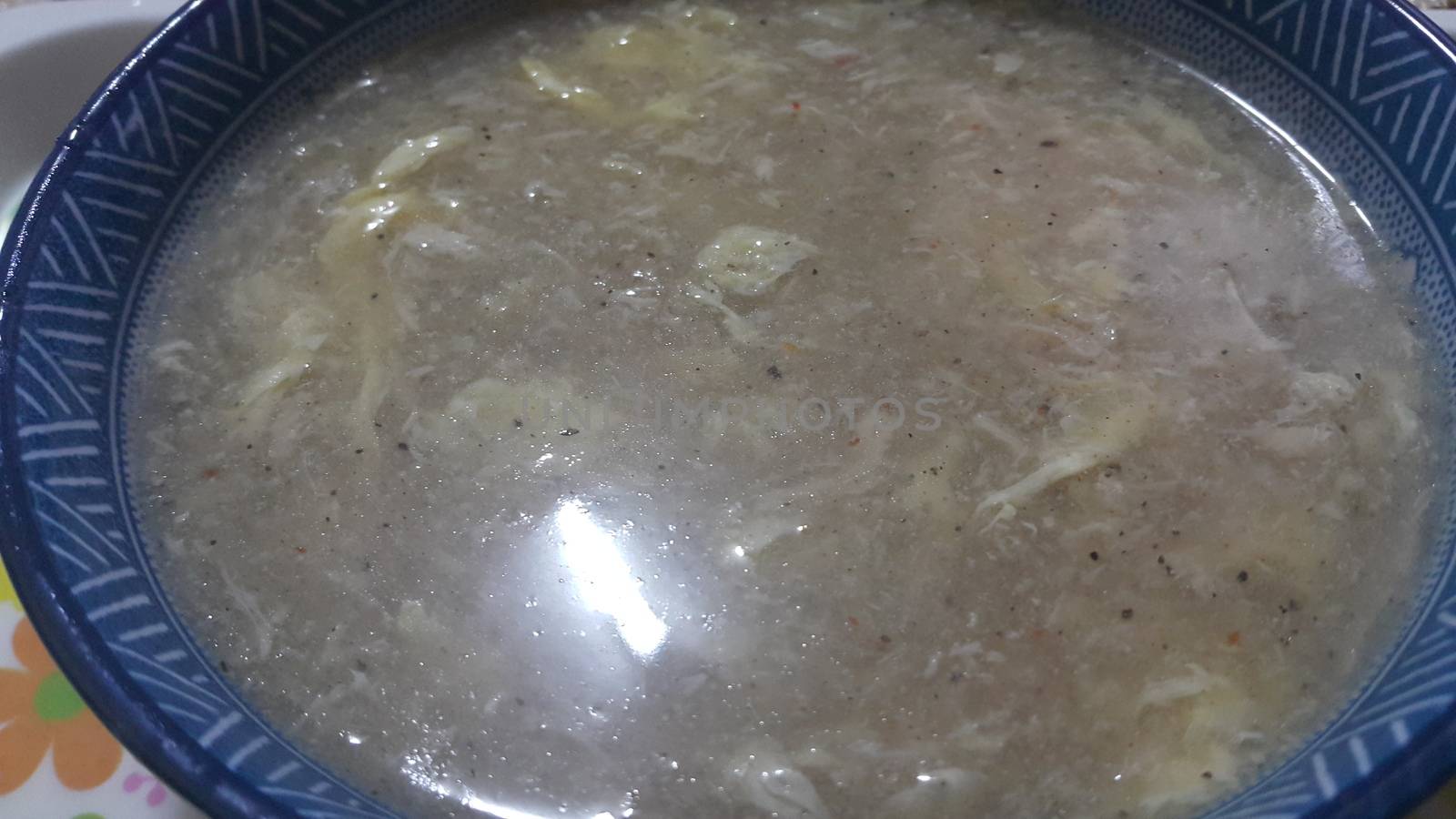 Close view of bowl of chinese spicy soup with egg, shiitake mushrooms, tofu and green onions. Soup background.