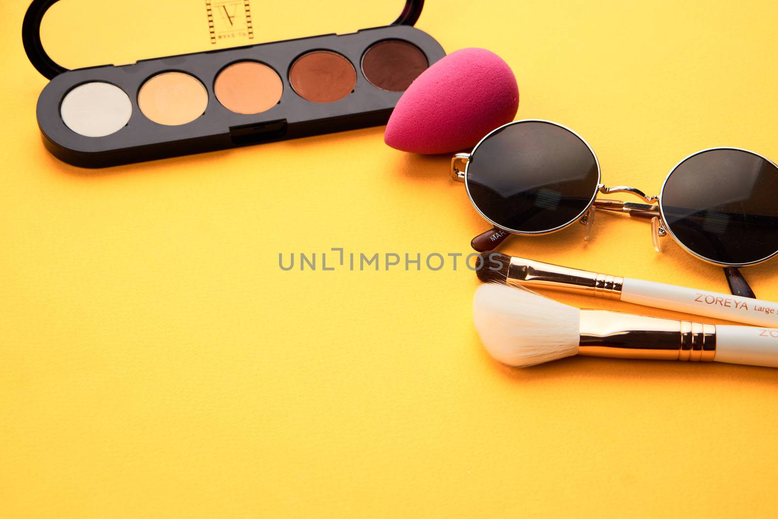 Eyeshadows on a yellow background professional cosmetics makeup brushes soft sponge fashion glasses. High quality photo