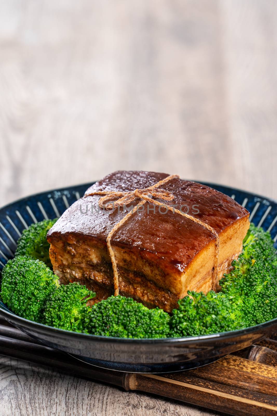 Dong Po Rou (Dongpo pork meat) in a plate with green vegetable, traditional festive food for Chinese lunar new year cuisine meal, close up.