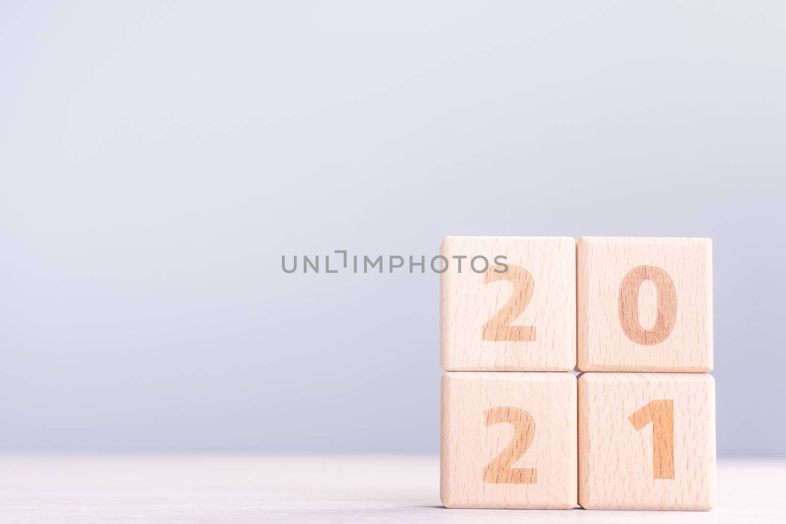 2021 New Year abstract design concept - Number wood block cubes isolated on wooden table and light mist blue background.