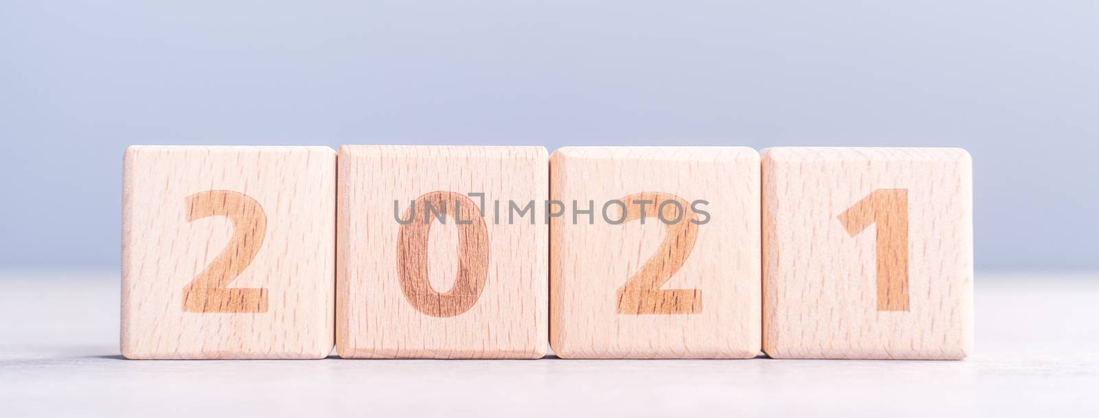 2021 New Year abstract design concept - Number wood block cubes isolated on wooden table and light mist blue background.