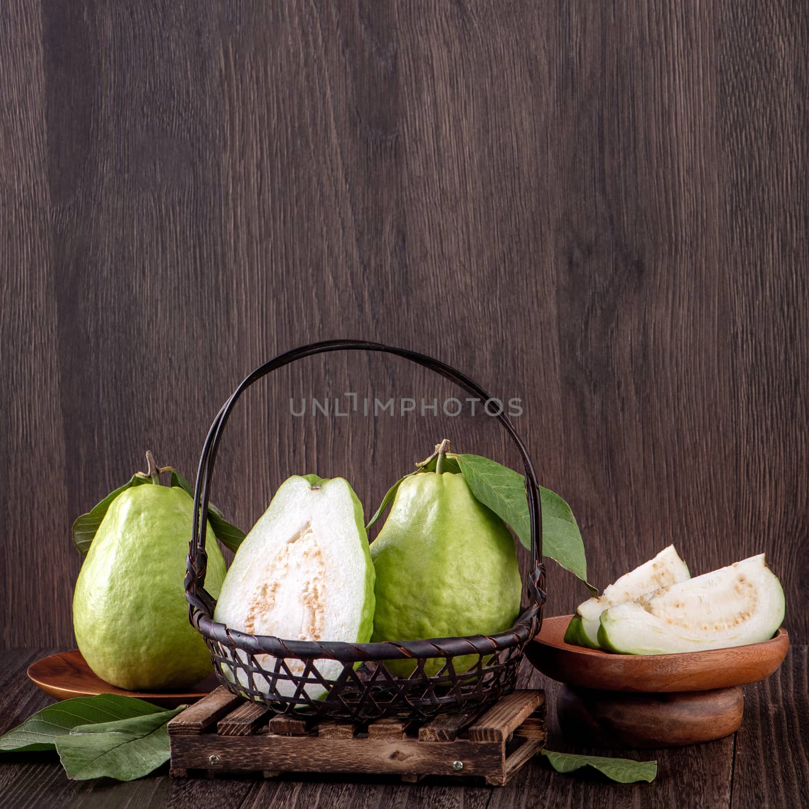 Delicious beautiful Guava set with fresh leaves isolated on wooden table background, close up.