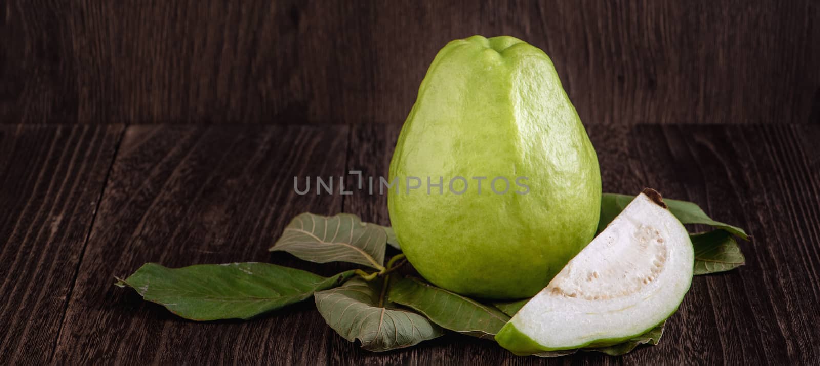 Delicious beautiful Guava set with fresh leaves isolated on wooden table background, close up.