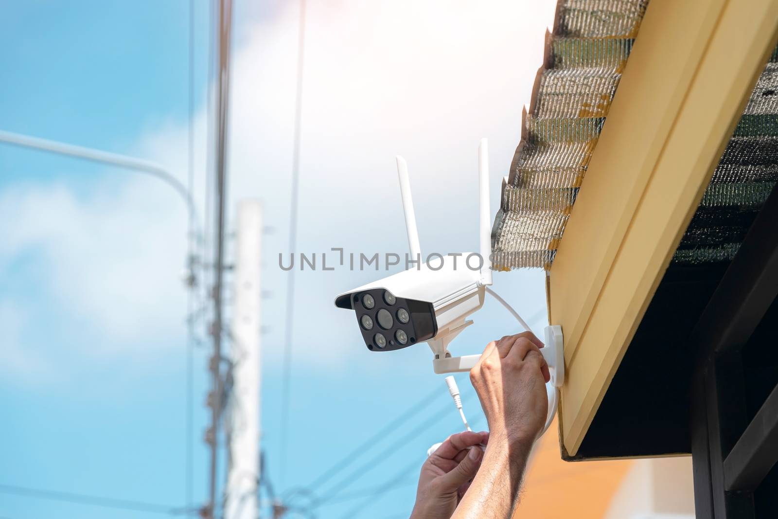 Technicians are installing a wireless CCTV camera on the front of the house to maintain security.