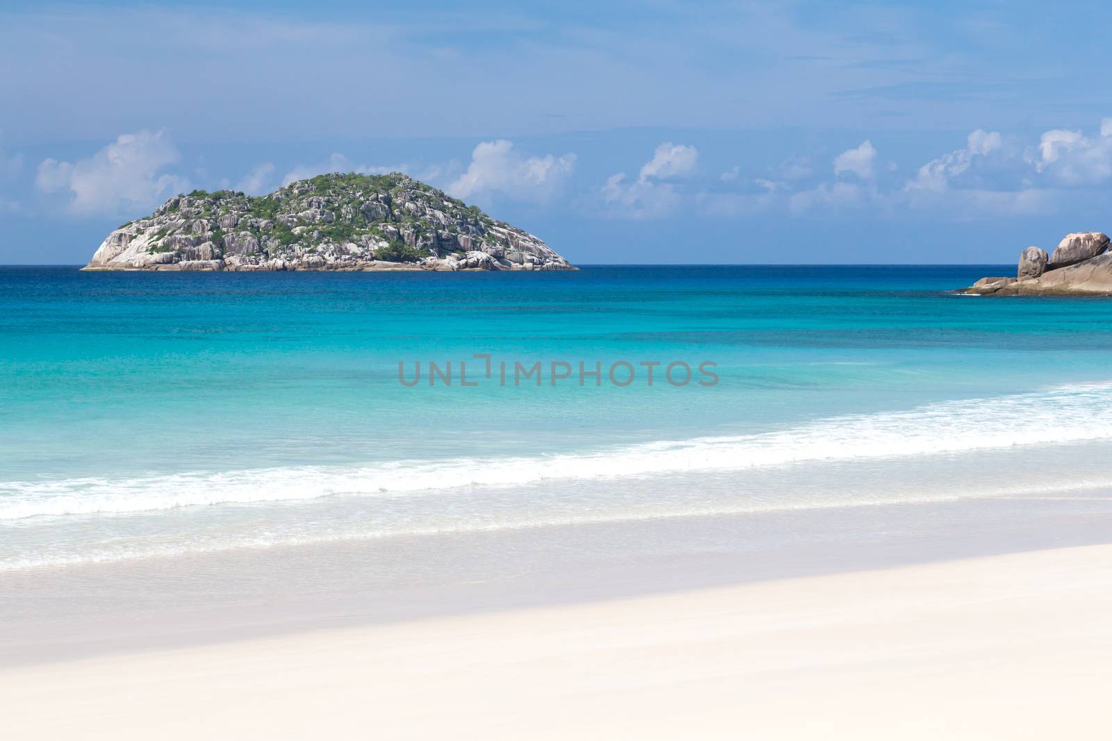 Beach with white sand and blue water with a view to the small island