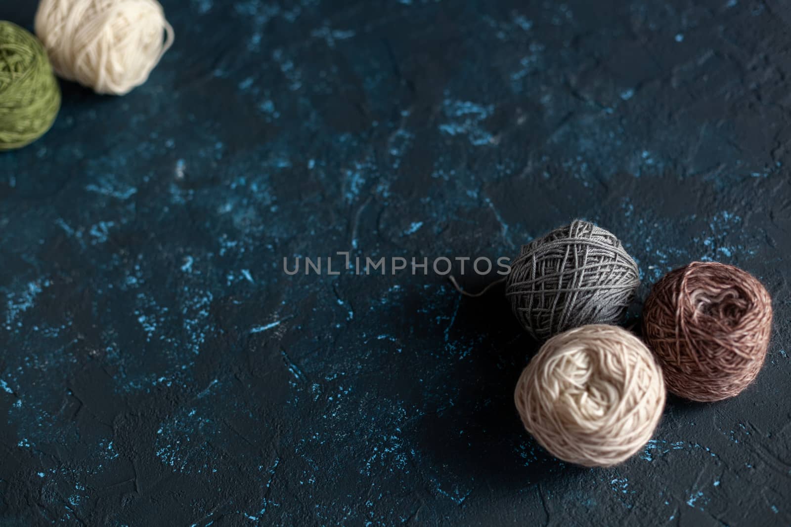 Color balls skein of wool yarn for crochet and knit on dark blue texture putty concrete. Flatlay image with space for text.