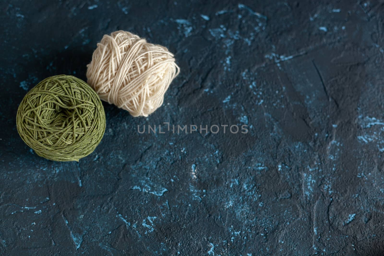 Color balls skein of wool yarn for crochet and knit on dark blue texture putty concrete. Flatlay image with space for text.