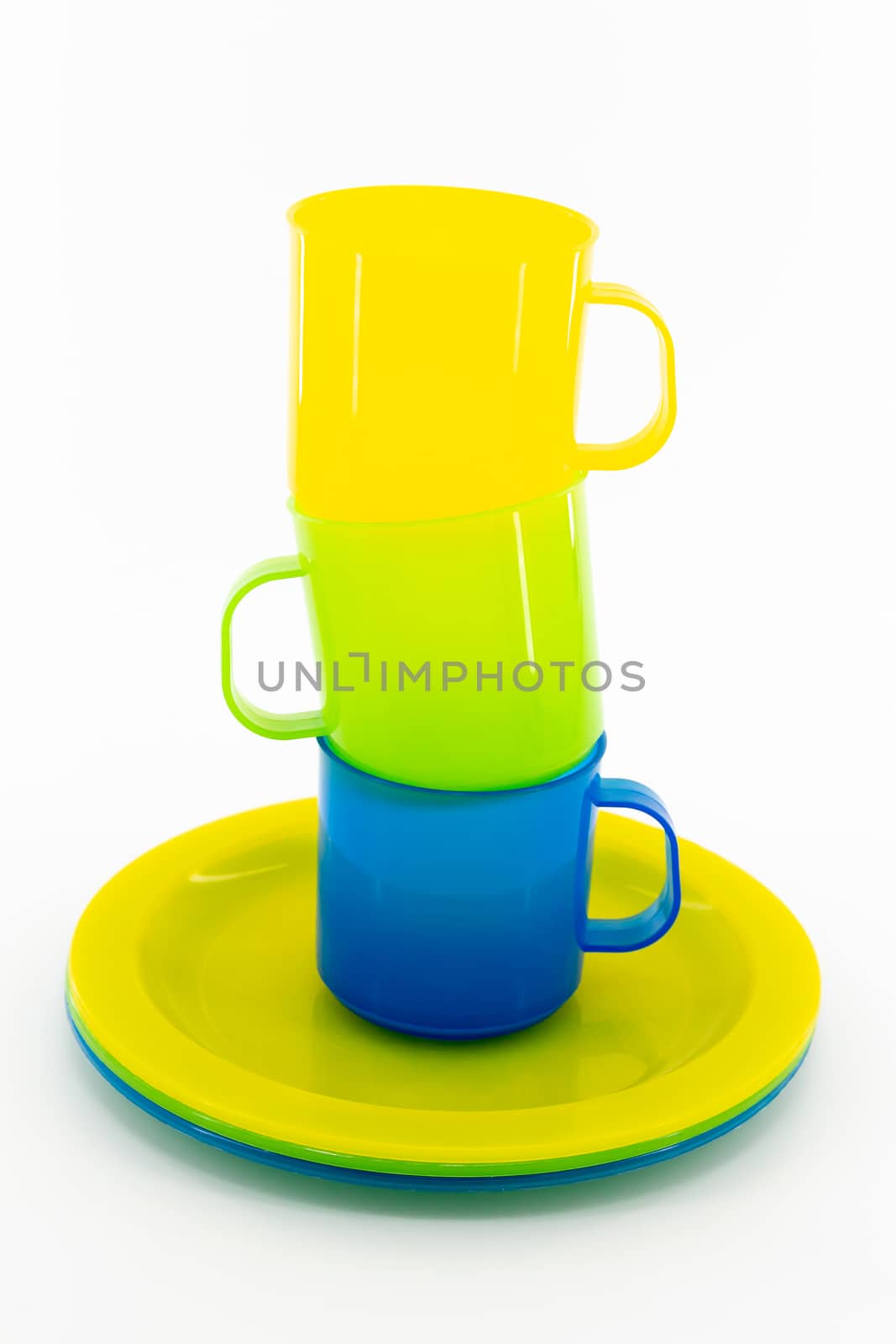 The three colored mugs and three colored saucers on a white background