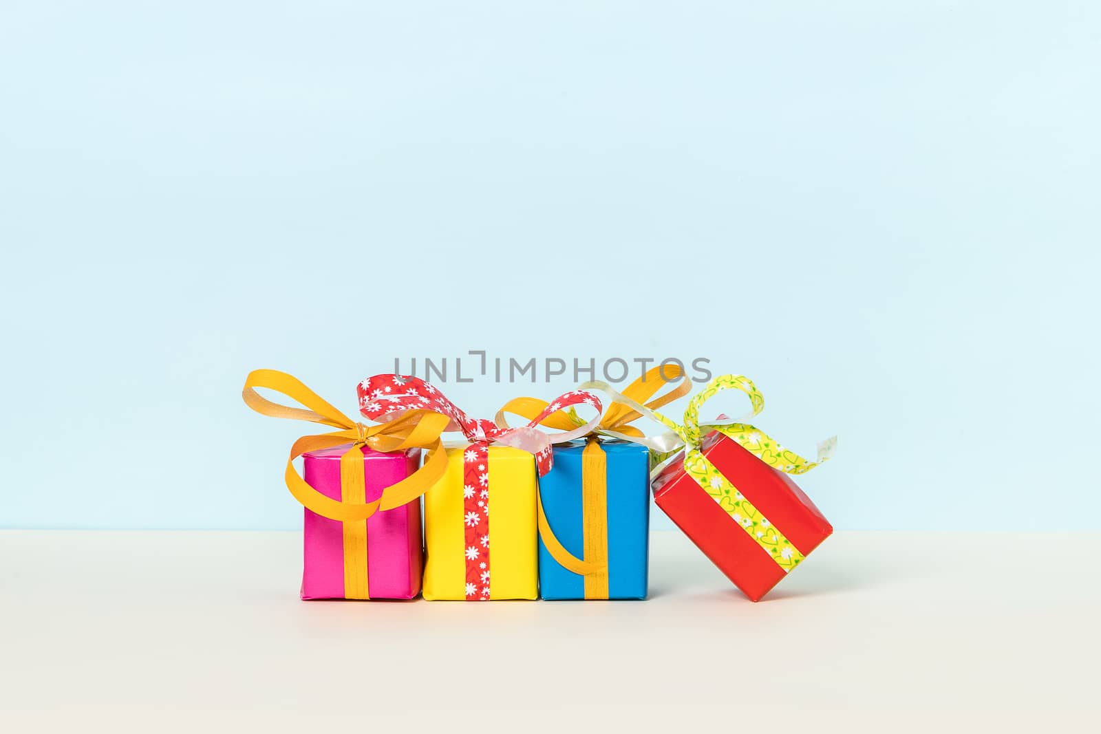 Four colorful gift boxes on a pastel background. Copy space. Front view.