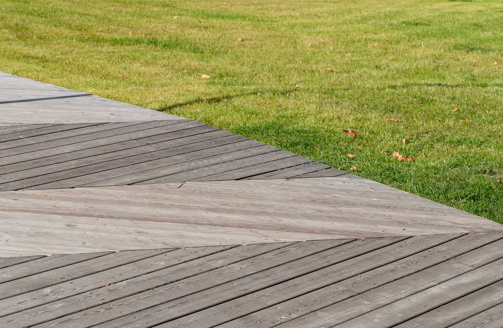 Pedestrian path made with wooden planks on the floor in a modern green city park.