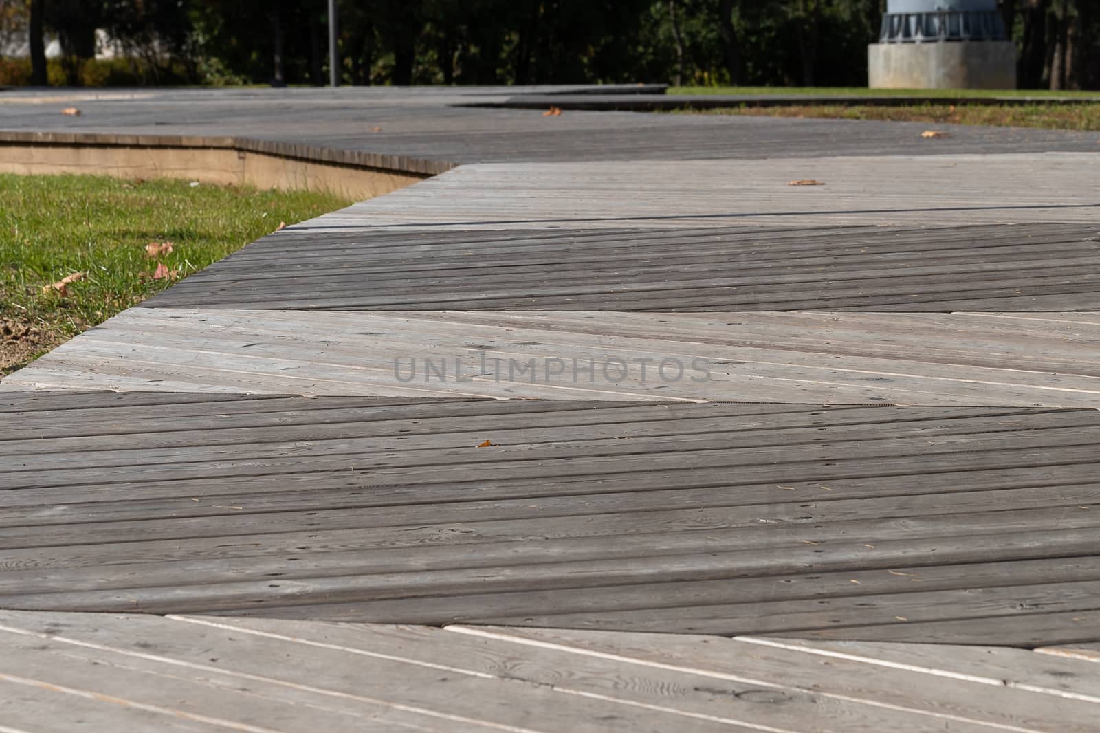 Pedestrian path made with wooden planks on the floor in a modern green city park. Selective focus.