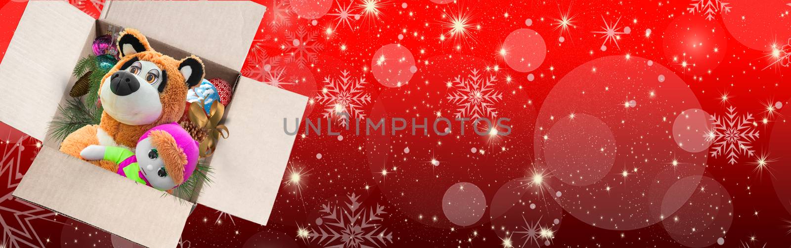 An open box with toys and Christmas decorations on a beautiful red background with bokeh and snowflakes, a Christmas gift for children. Greeting card, banner.