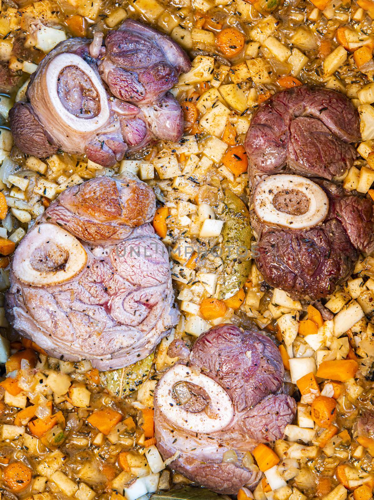 Osso buco in bianco is traditional Italain dish from the Milan area. The veal meat slices with marrow bone are being cooked in a large casserole along with root vegetables, spice and wine sauce