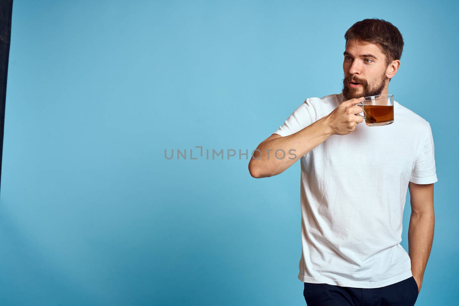 Man with a cup of tea on blue background cropped view of fun emotion Copy Space by SHOTPRIME