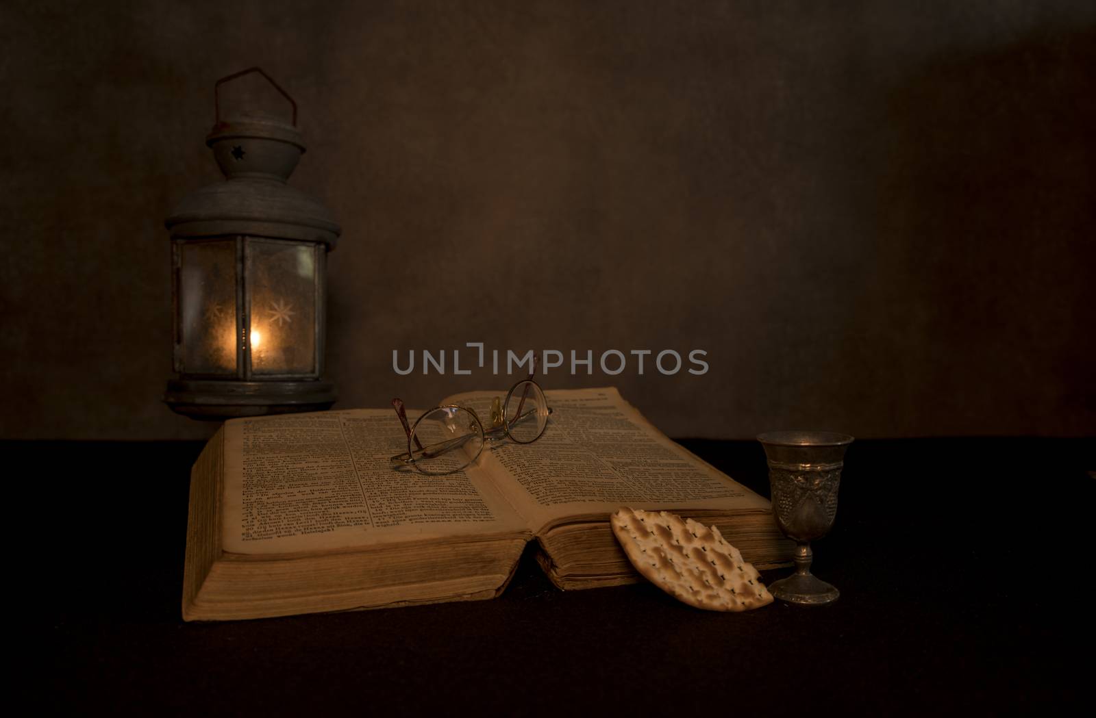 a still life of a bible with an old pewter lamp with a tea light burning with an old bible and supper