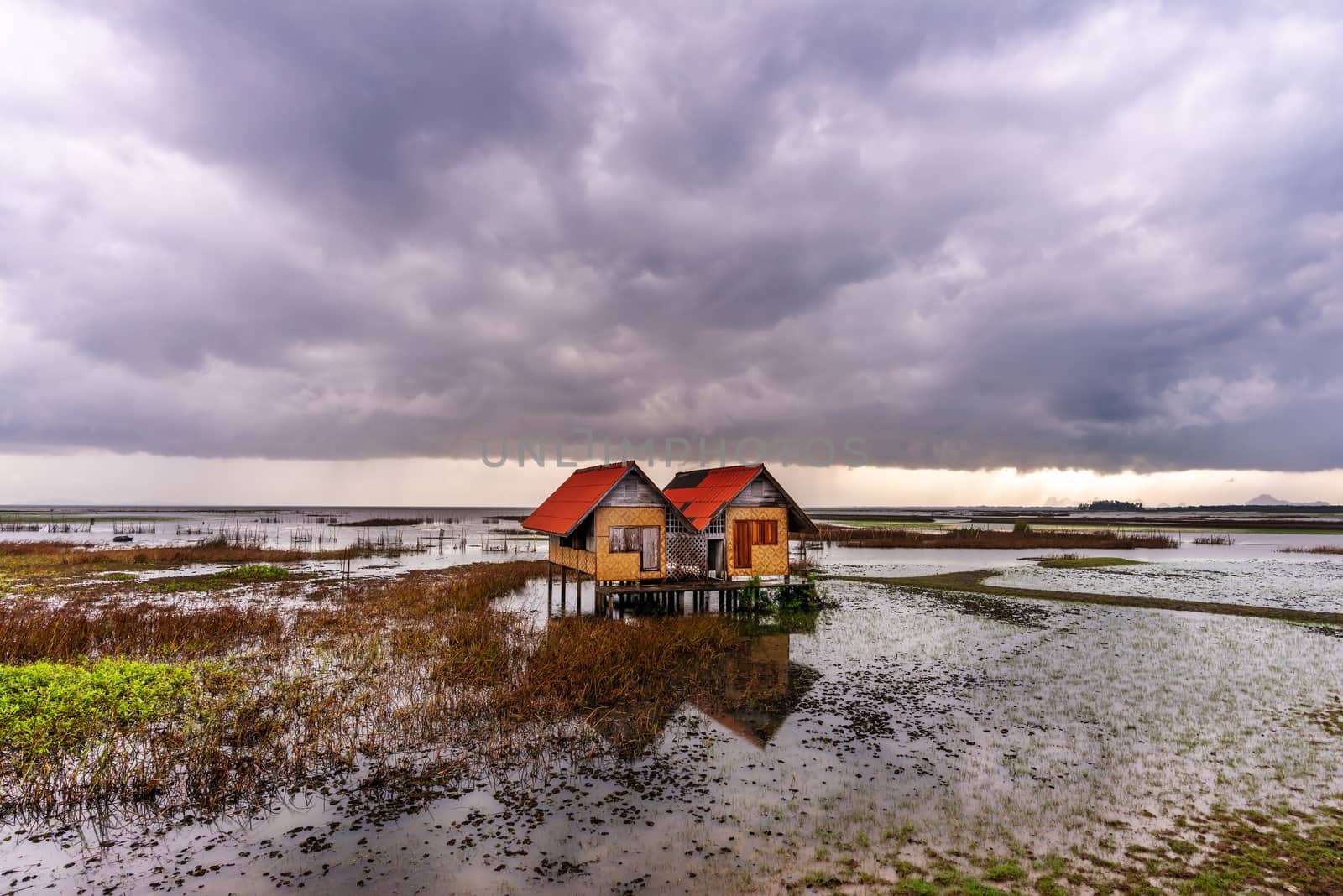 View of an abandoned house in the middle of the lake with sky and cloud rain in sunset