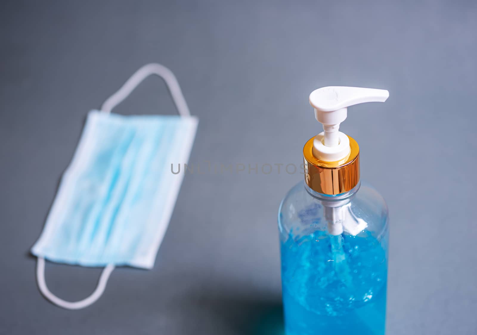 Alcohol gel with mask on blurred grey background, Corona virus or covid-19 concept