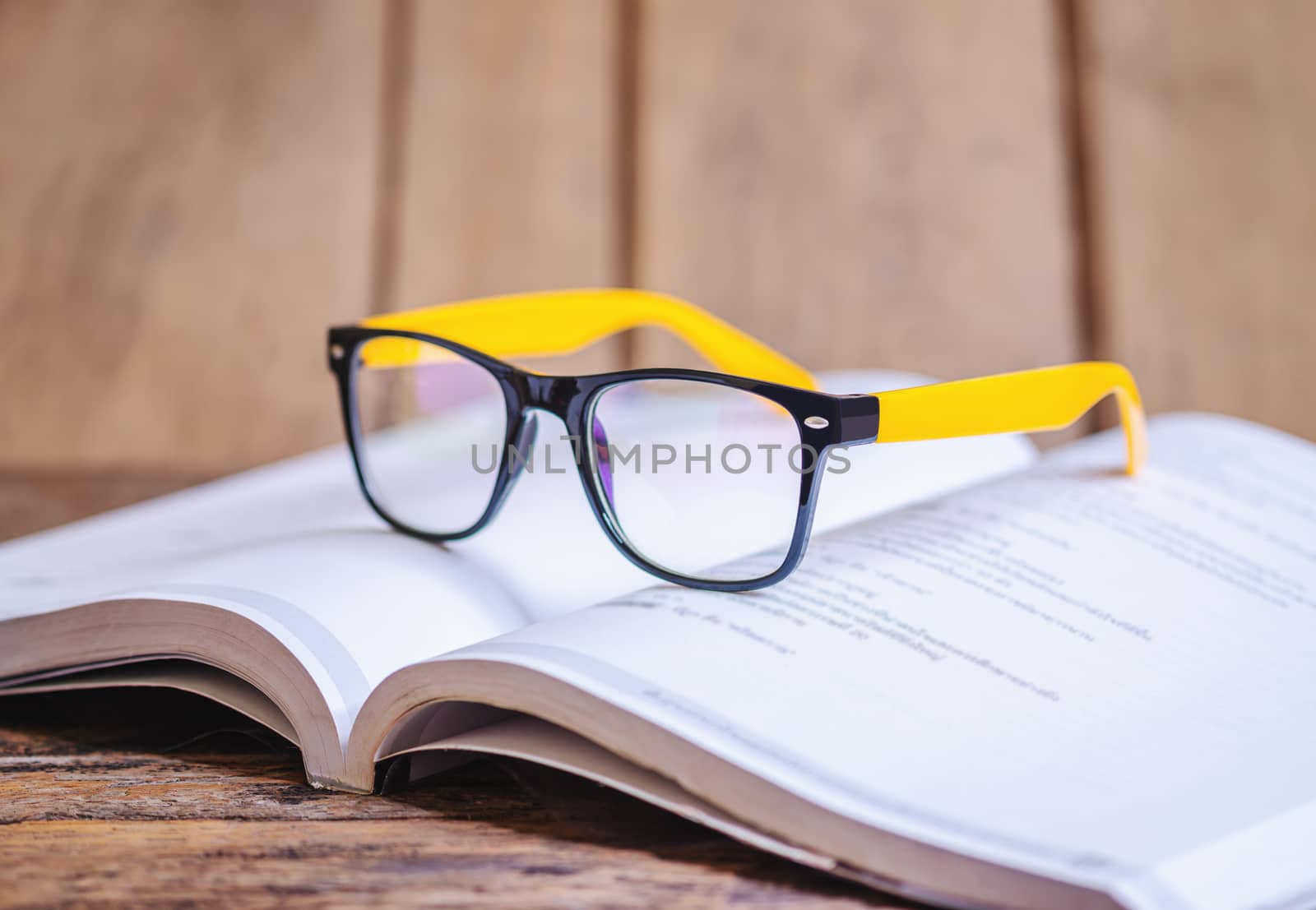 Glasses on the book blurred background by Suwanmanee