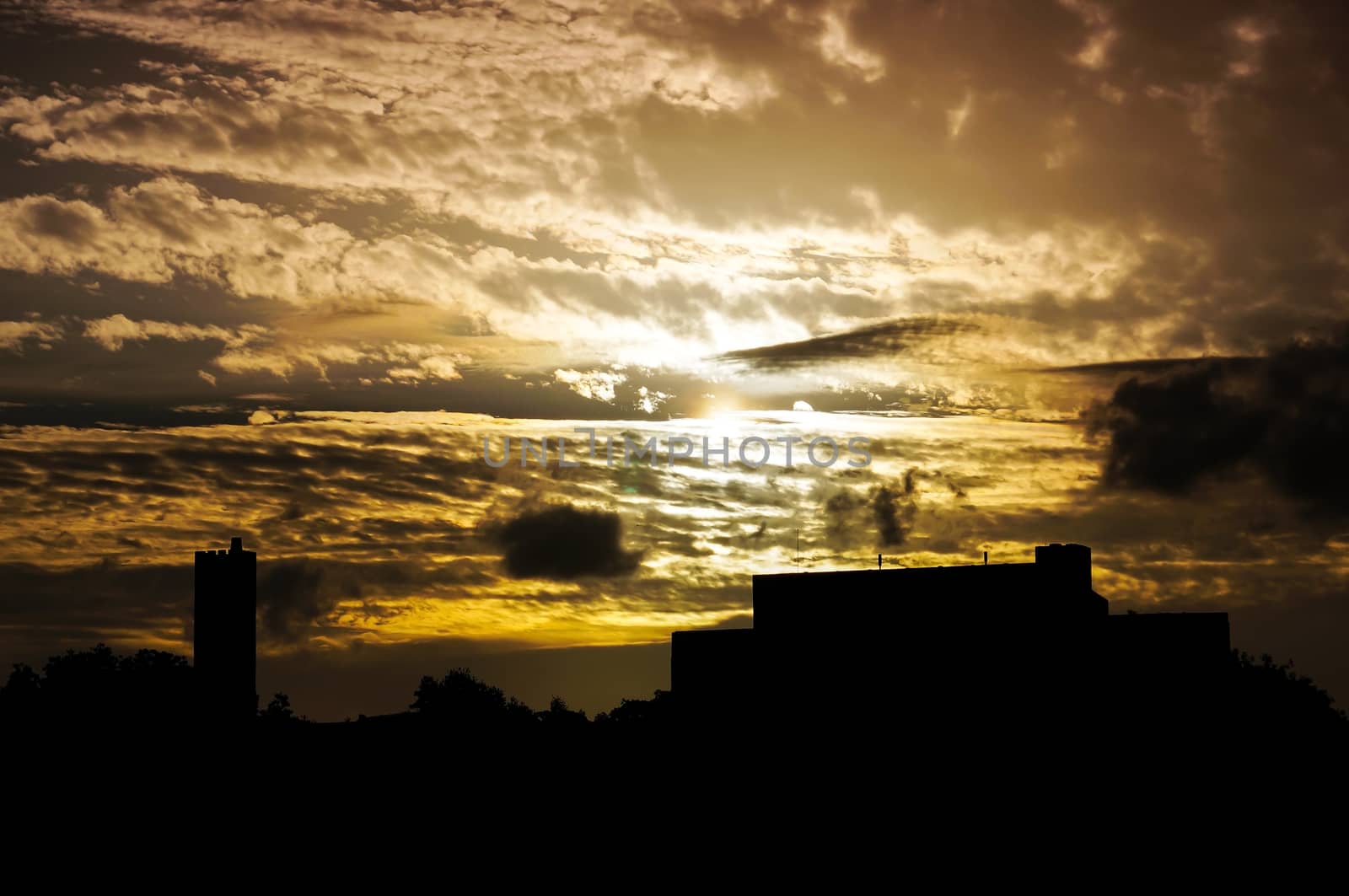 Silhouette building with dramatic sky with cloud storm and color of the sunset in twilight