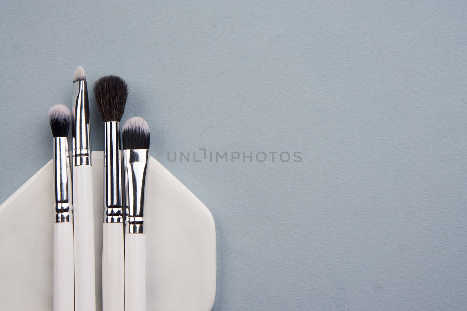 professional makeup brushes on stand on gray background and copy space cropped view by SHOTPRIME