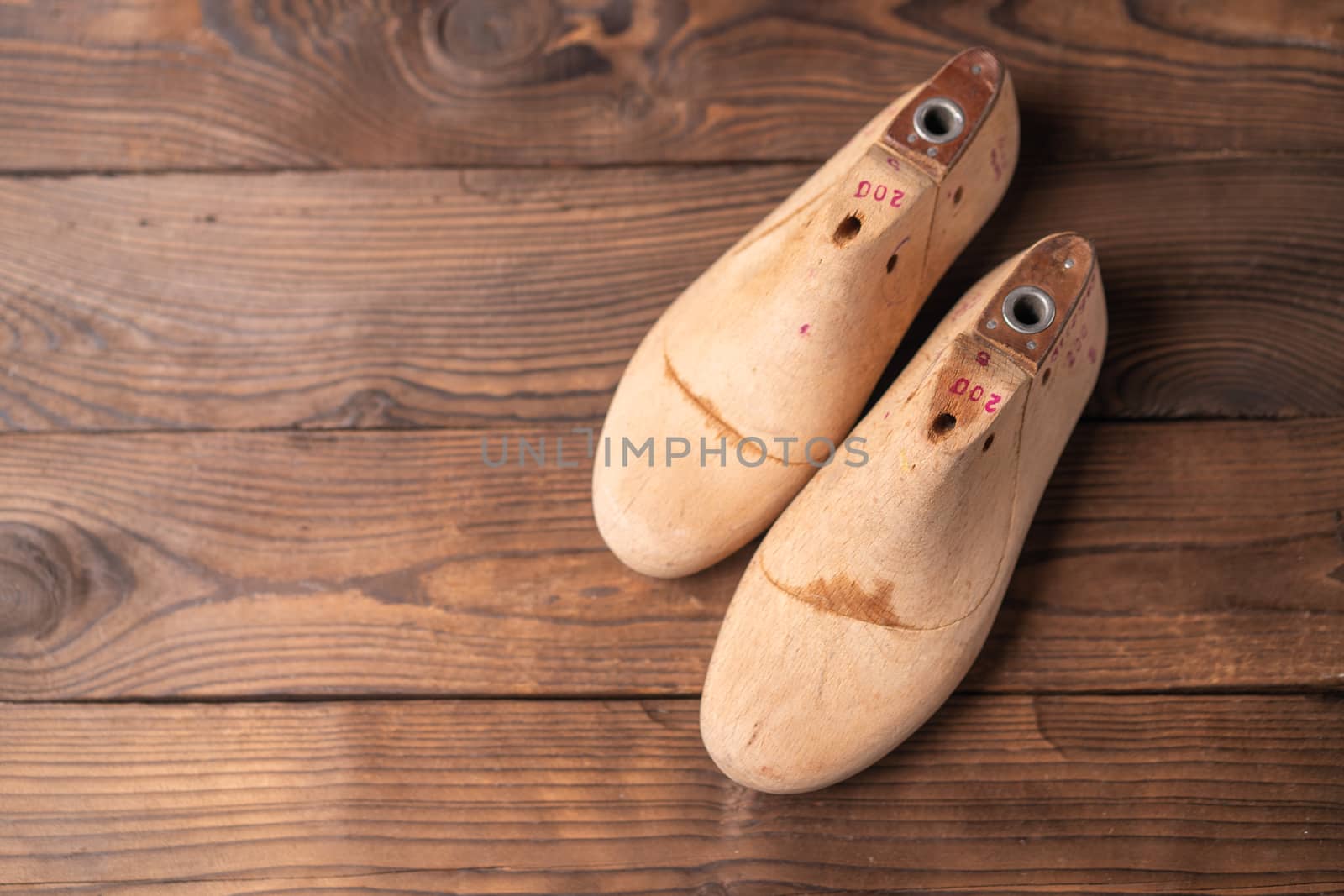 Leather samples for shoes and wooden shoe last on blue wooden table. Designer furniture clothes. Shoe maker workspace.