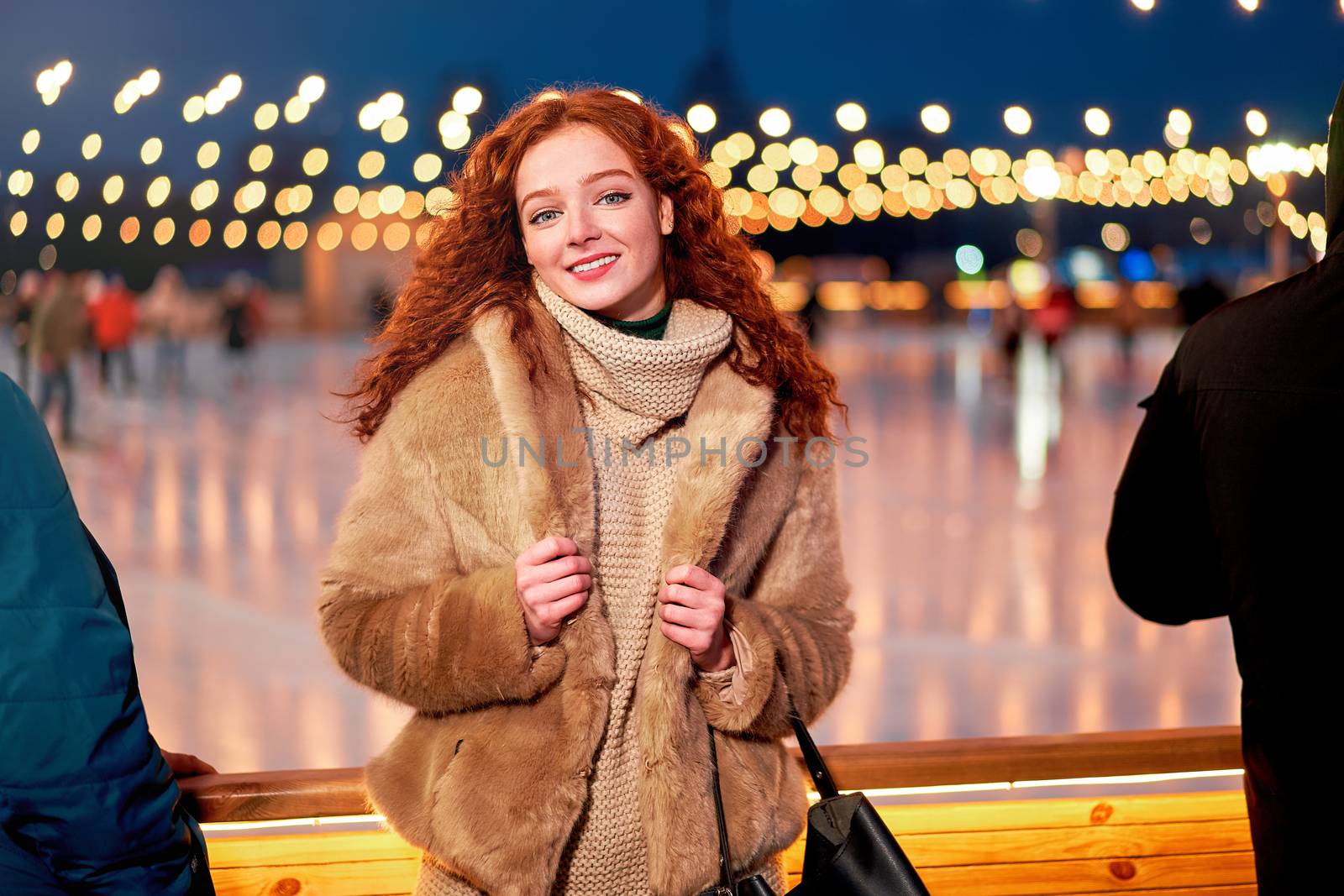 Young beautiful redhead girl freckles ice rink background Pretty woman curly hair portrait walking new year fair Modern cute female drink hot beverage mulled wine chrismas holiday decorated street.