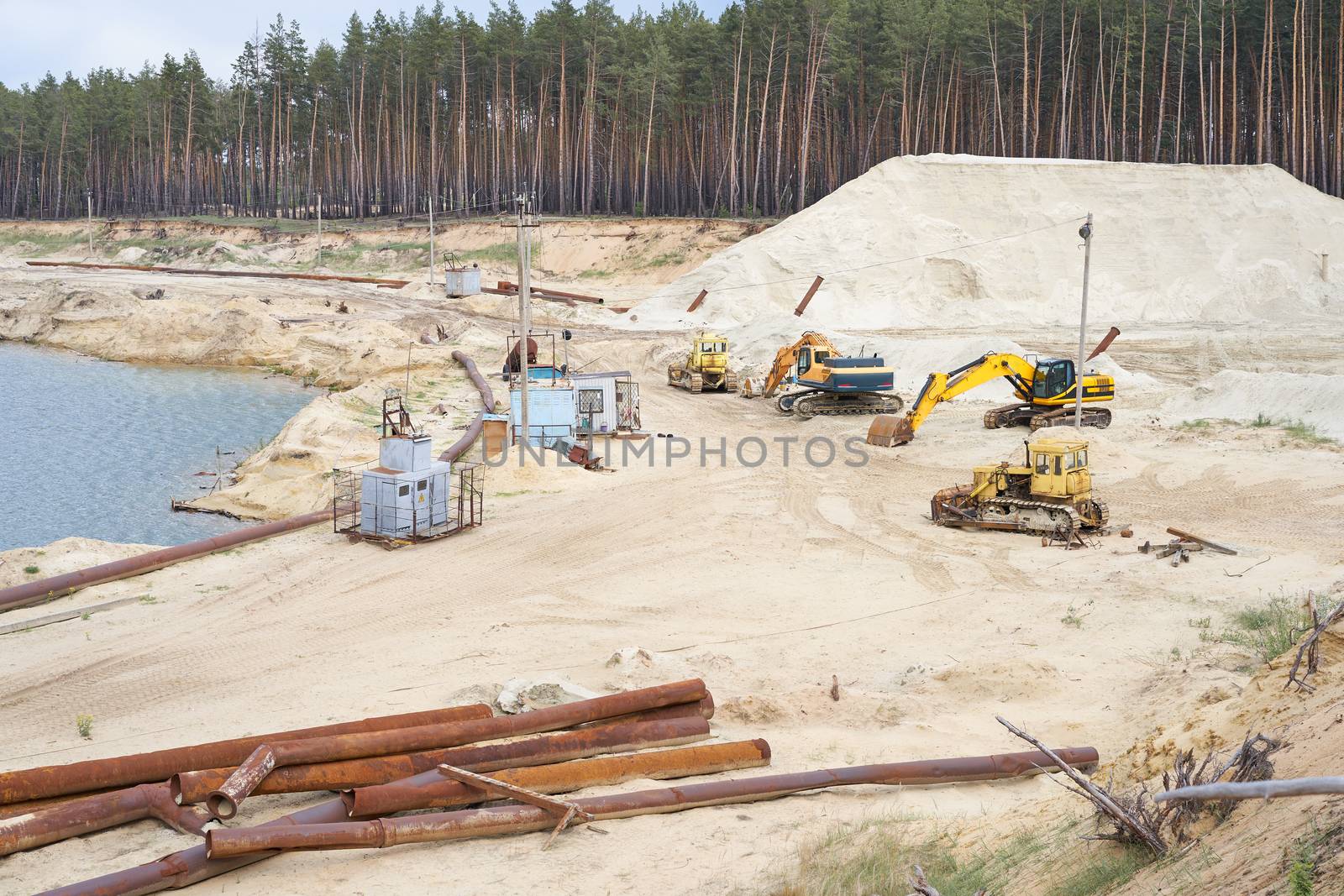 Sand quarry mining industry equipment excavator tractor standing sand land near lake water Industrial activity mine operation summer sunny day. Ecology problem Non-renewable resources of the Earth