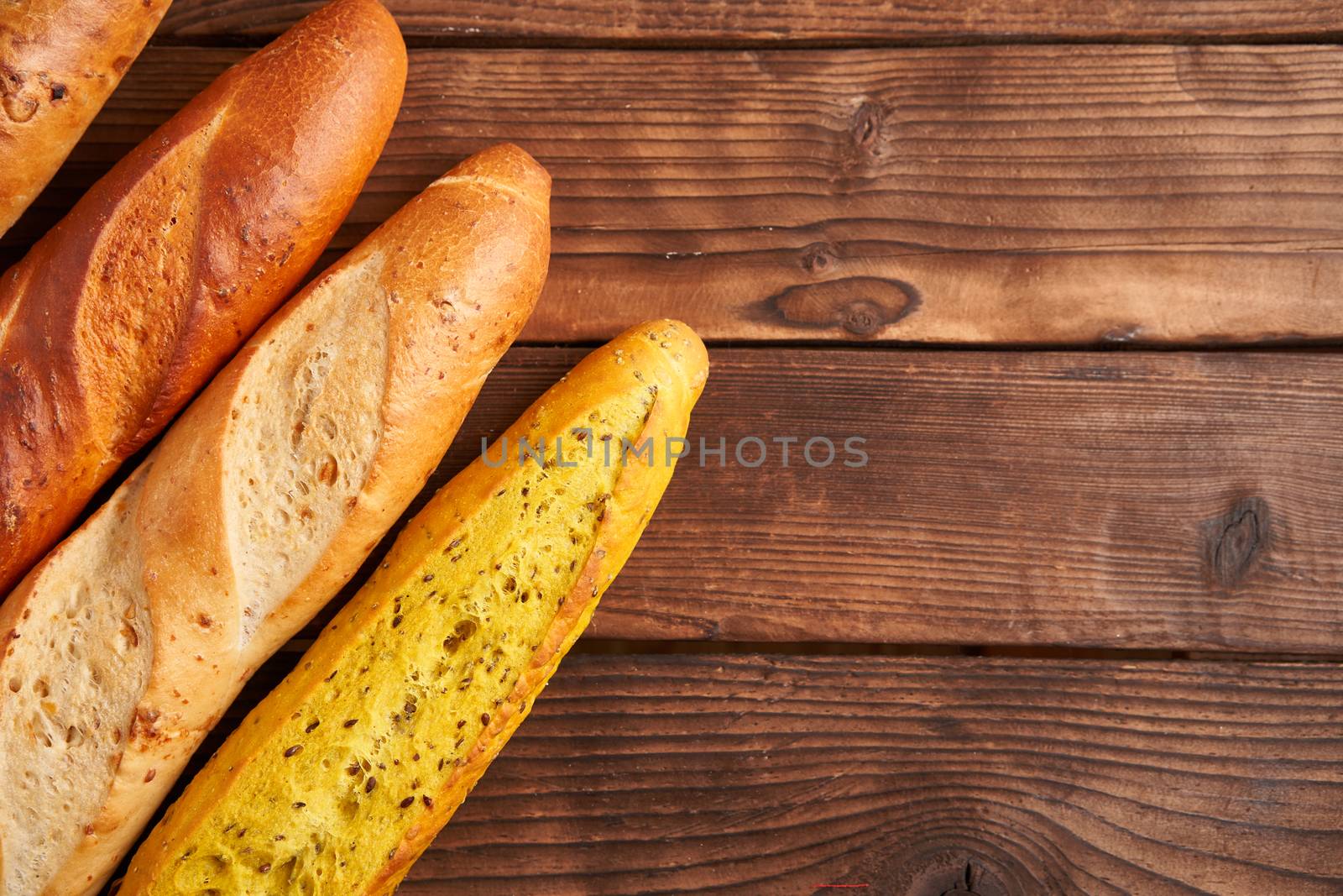 Three crispy french baguettes lie on an old wooden table with free space for text baguettes in assortment with sesame seeds Classic french national pastries Copy space Concept for menu or advertising