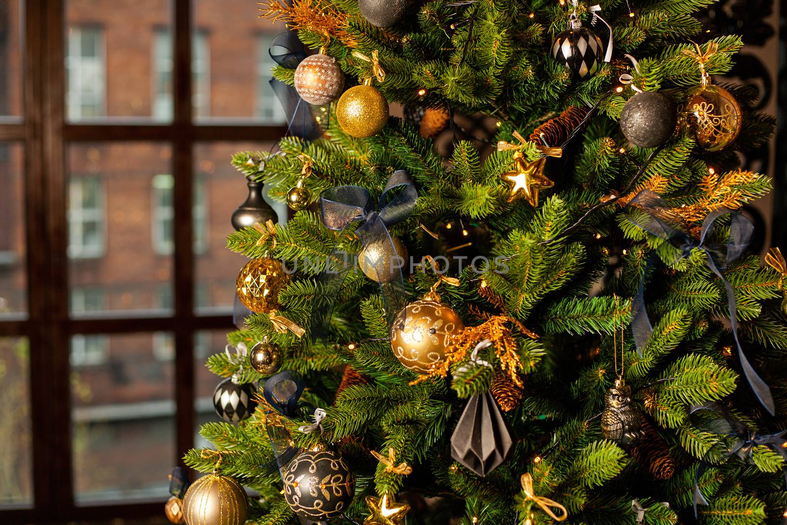 Close-up of a Christmas tree decorated with gold balls and blue bows. Christmas holiday concept. Free space for text