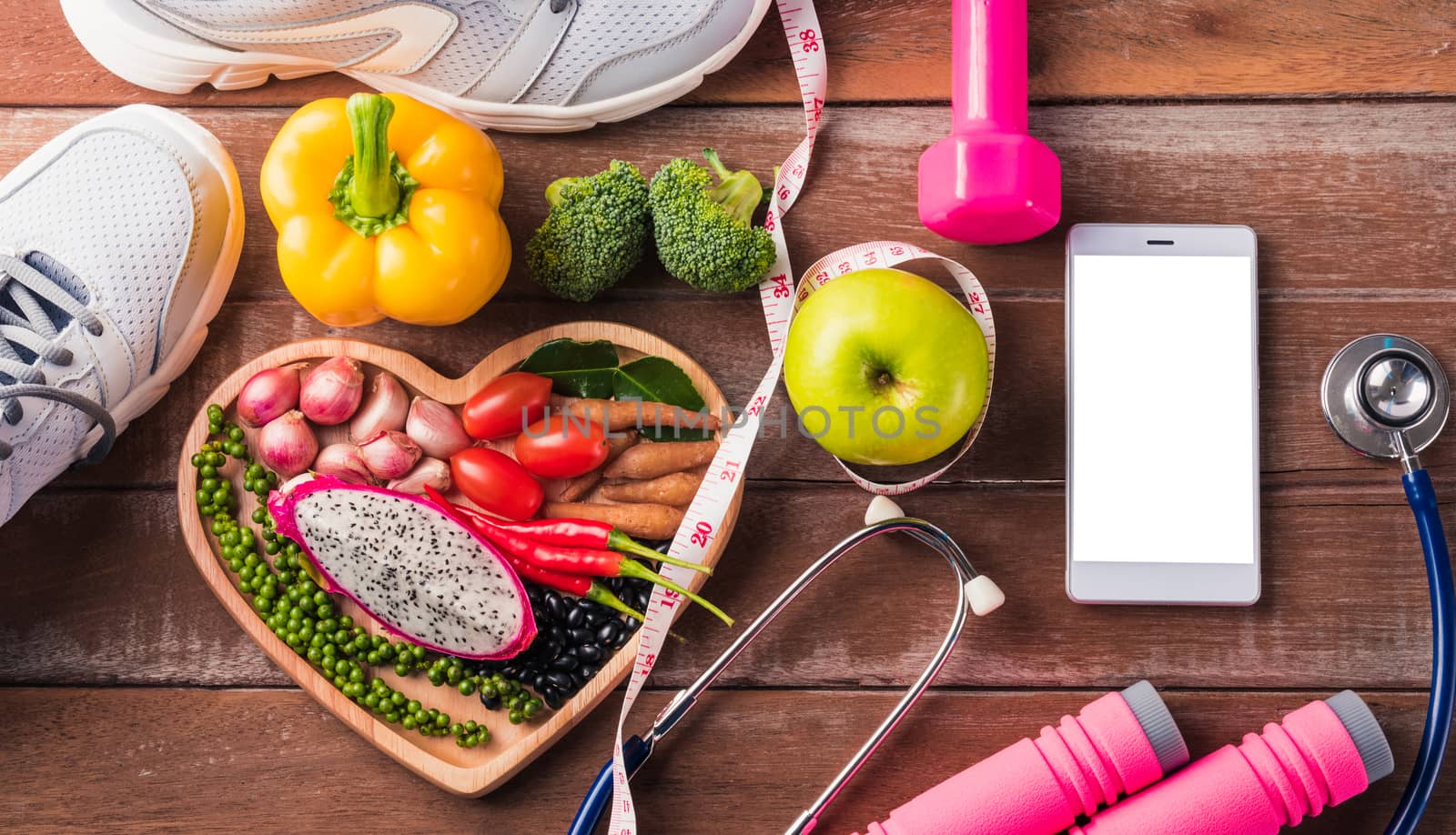 Top view of fresh organic fruit and vegetable in heart plate, shoes, sports equipment and doctor stethoscope, studio shot on wooden gym table, Healthy diet vegetarian food concept, World food day